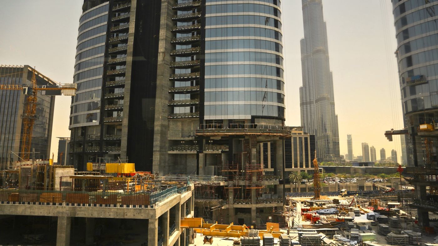 Active construction site in Downtown Dubai with tower cranes, scaffolding and the Burj Khalifa in the background