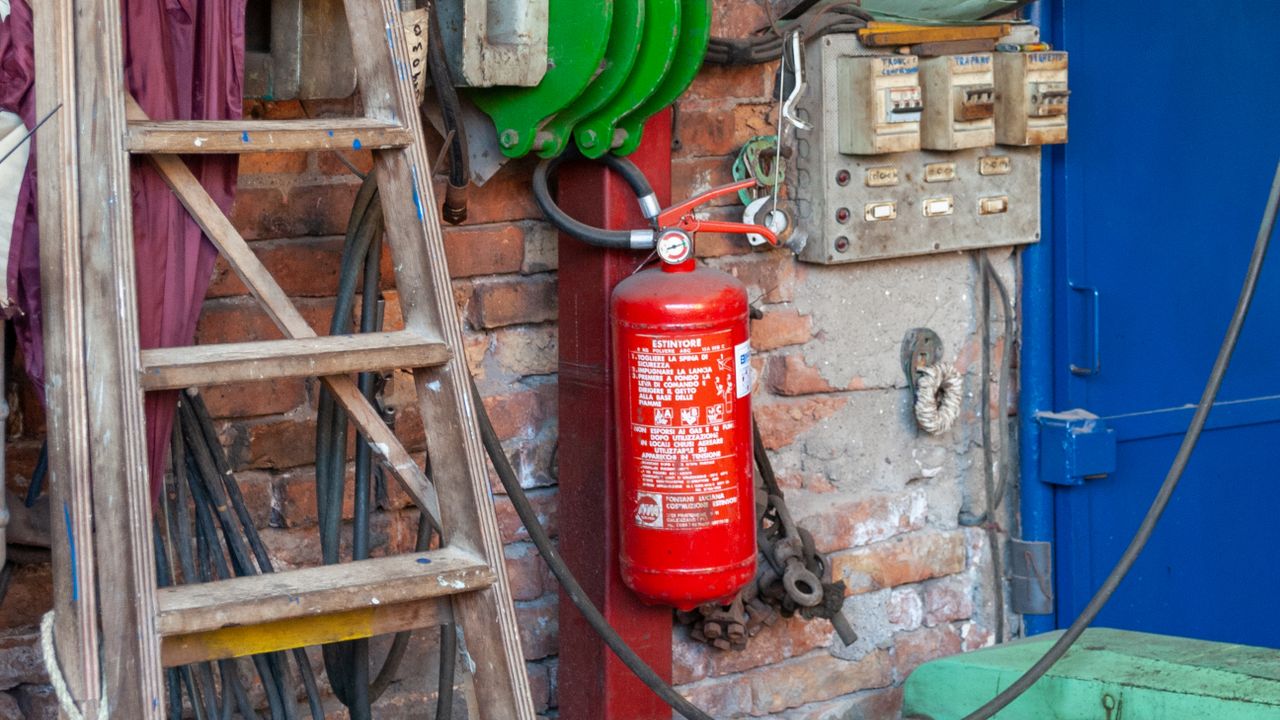 Fire extinguisher mounted by an electrical panel in an industrial workshop