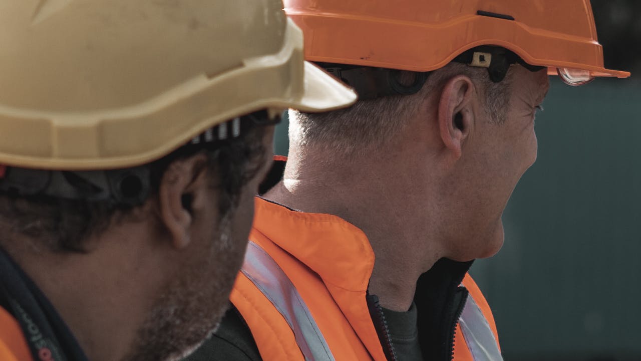 Two workers wearing hard hats and high-visibility safety vests on site